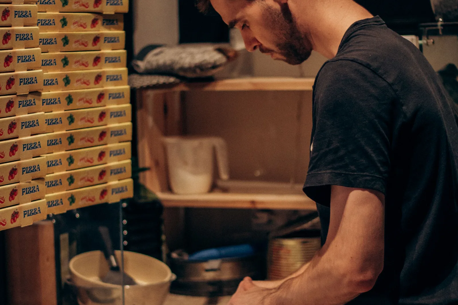 A cook working the prep line with delivery boxes stacked behind