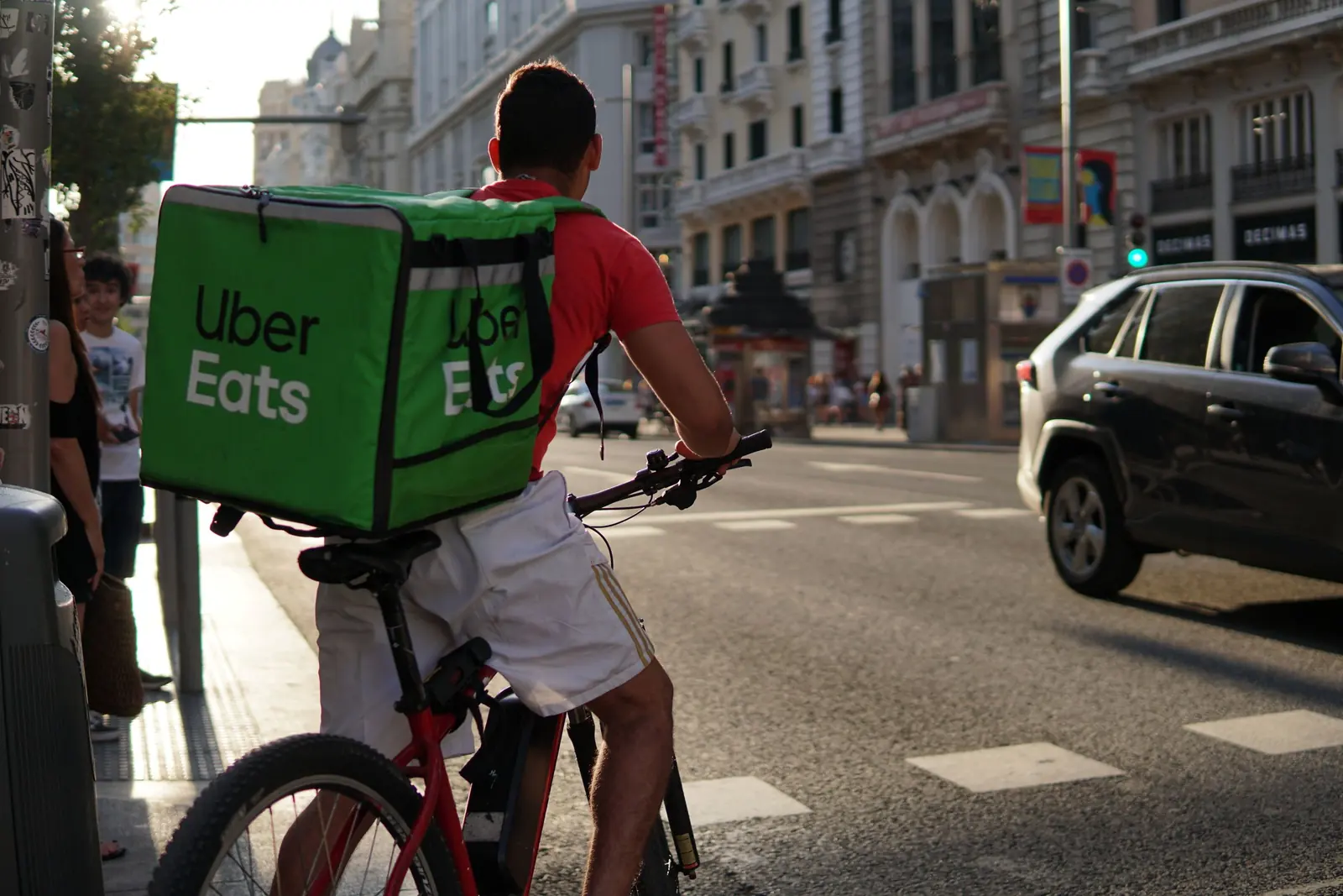 Courier cycling through the city with a delivery bag on their back