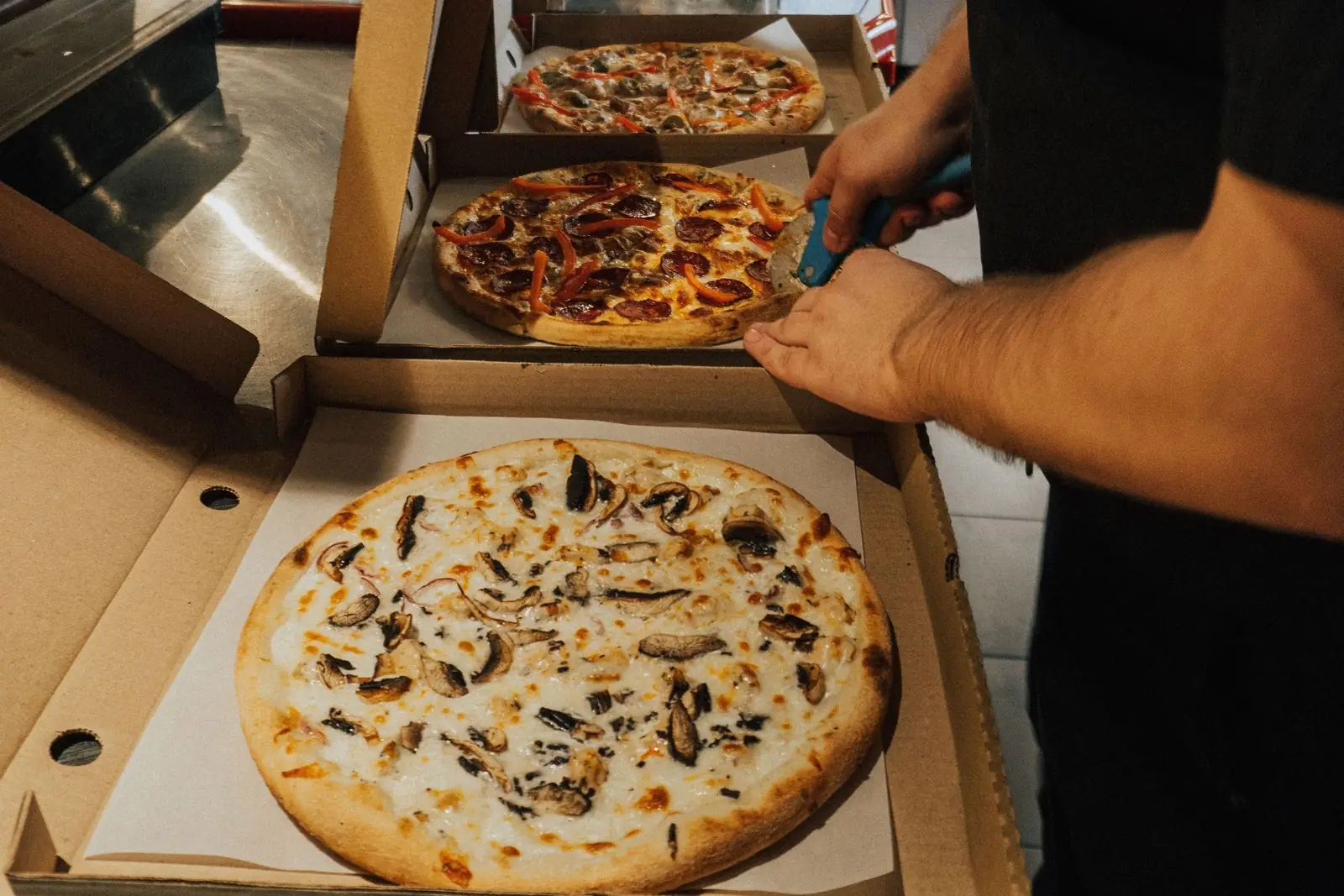 Pizzas being placed into delivery boxes in a kitchen
