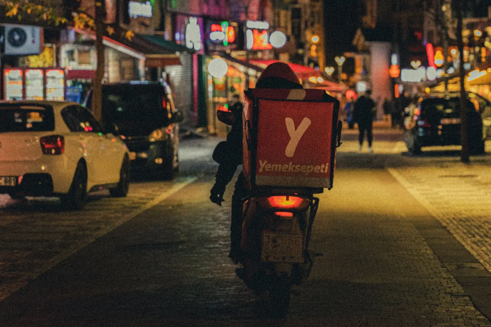 Motorcycle courier carrying a delivery order along a street at night