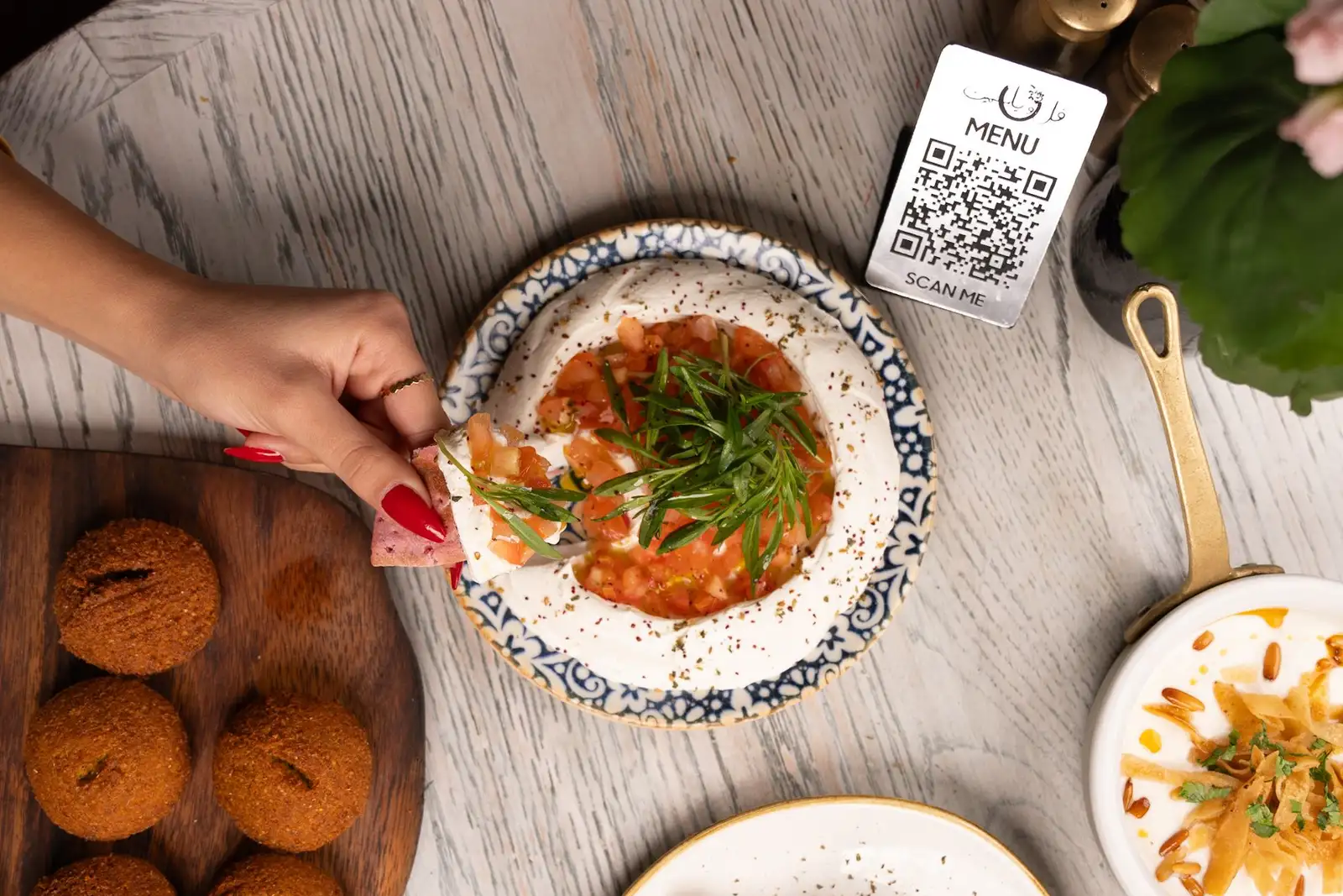 A QR menu card on a restaurant table alongside plated dishes
